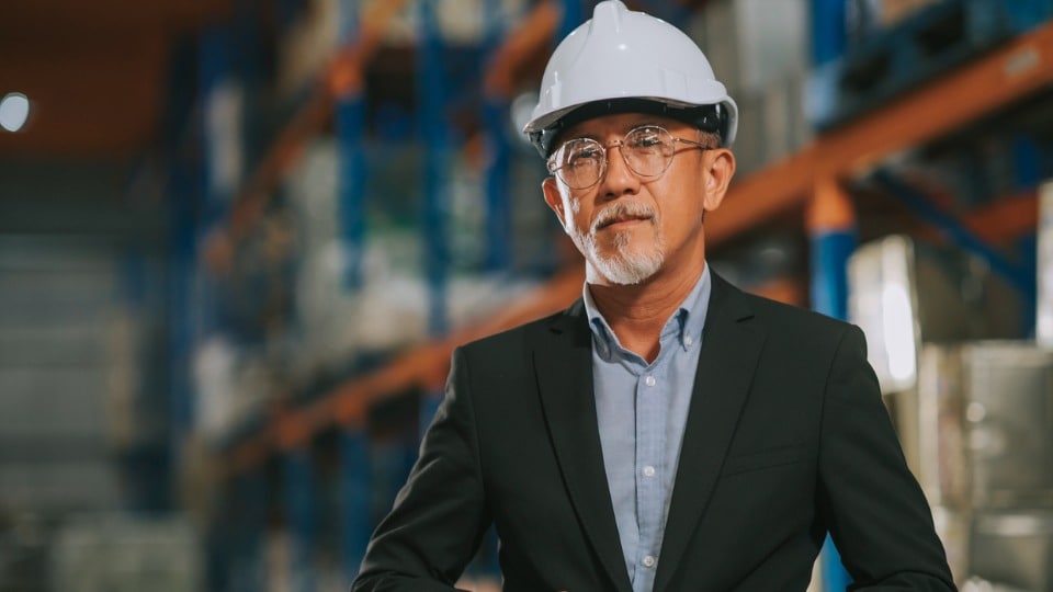 Freight manager with white hardhat looking at the camera with serious face expression