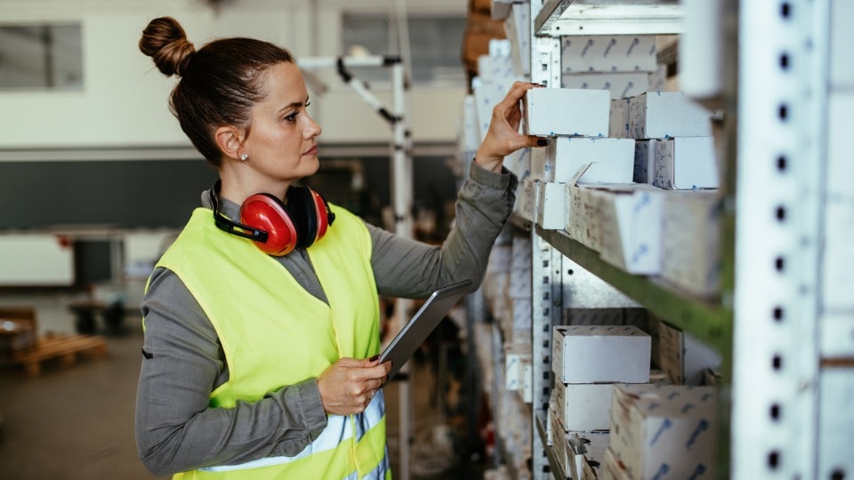 female worker in warehouse using digital tablet to check stocks and spare parts