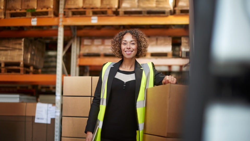 Female warehouse manager checking the stock of the loaded van, smiling into the camera