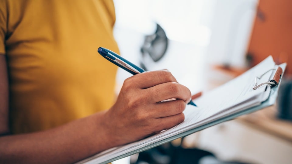 lady in yellow shirt filling out documents on a clip board